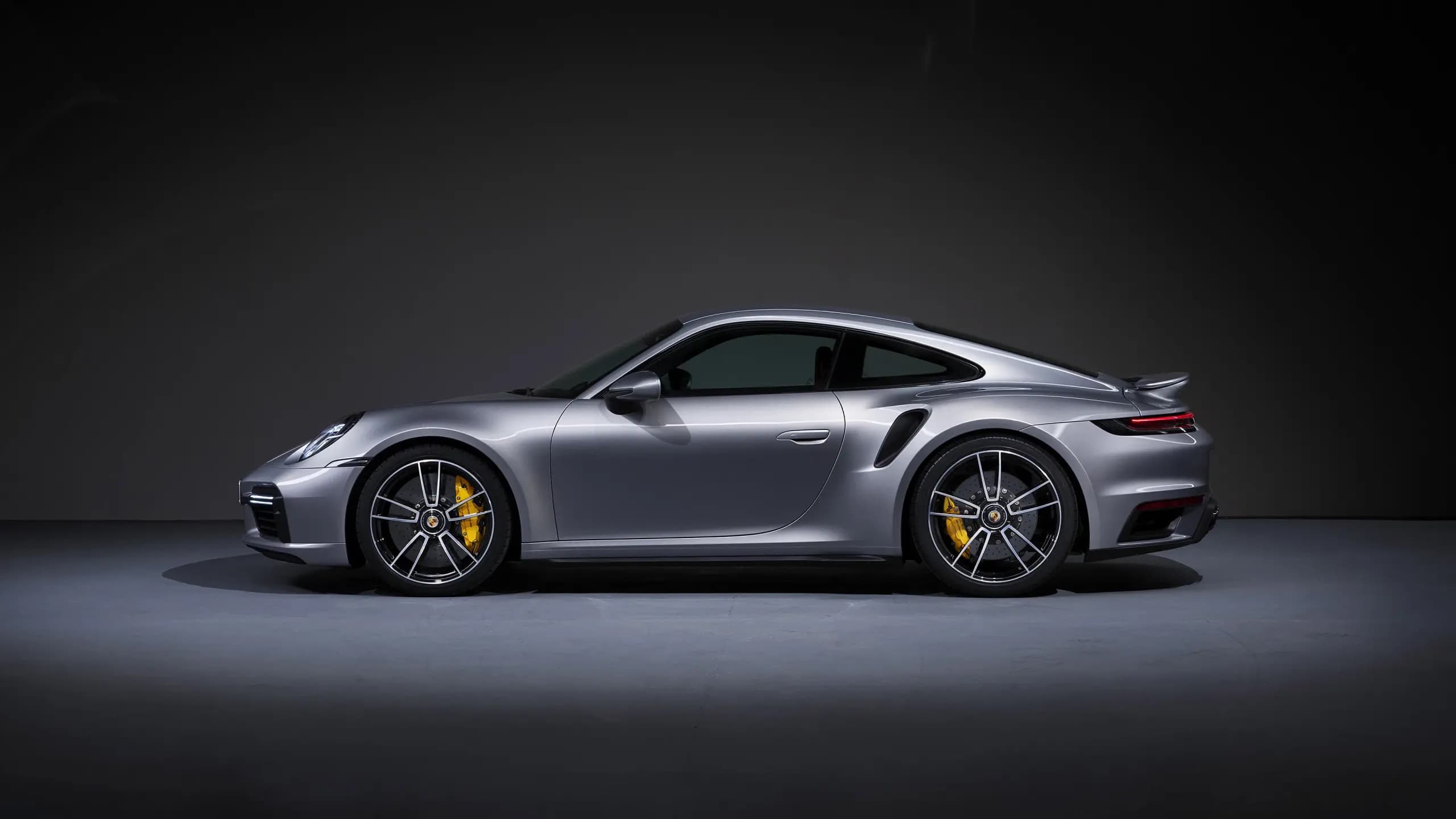 Porsche 911 Turbo S argentée de profil dans un studio sombre